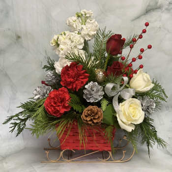 Holiday floral arrangement in a red basket with roses and carnations