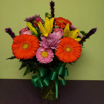 Bright mixed bouquet with gerbera daisies, lilies, and chrysanthemums in a glass vase