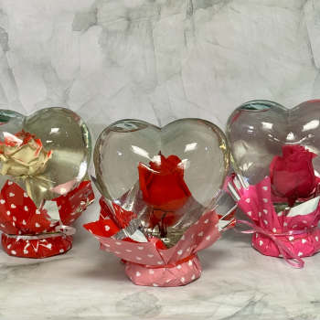 Three roses in heart-shaped glass holders with pink and red wrapping