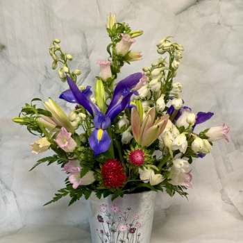 Mixed bouquet with purple irises and pink-white blooms in a decorative metal bucket