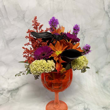 Halloween bouquet in an orange goblet vase with black spider and orange flowers