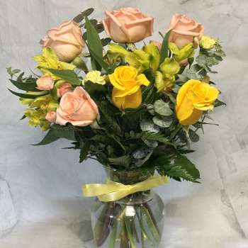 Peach and yellow roses with yellow alstroemeria in a glass vase