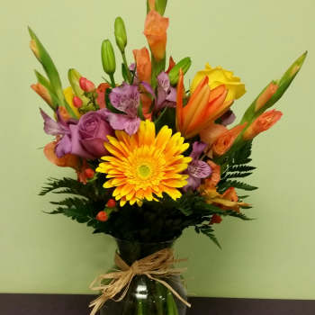 Mixed bouquet in a glass vase with yellow, orange, and purple flowers