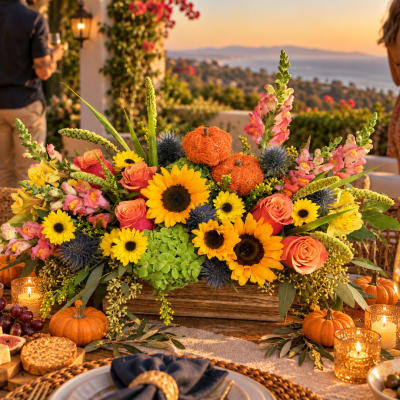 Large floral centerpiece with sunflowers, roses, and pink snapdragons in a wooden box