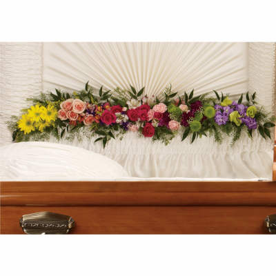 Colorful flower spray arranged across a white casket