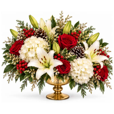 Red roses and white lilies in a gold pedestal vase with berries and pinecones