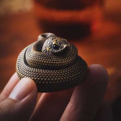 A small coiled snake figurine held between fingers