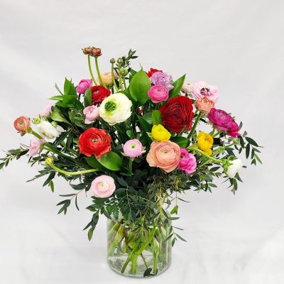 Mixed bouquet of colorful ranunculus in a clear glass vase
