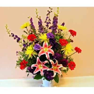 Colorful bouquet with pink lilies, purple flowers, and red and yellow daisies in a white vase