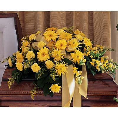 Yellow floral casket spray with ribbon on a wooden casket