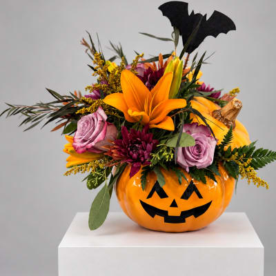 Halloween floral arrangement in a jack-o'-lantern container with roses and lilies