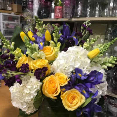 Bouquet of yellow roses, white hydrangeas, and purple flowers in a vase