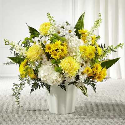 Yellow and white daisies, chrysanthemums, and hydrangeas arranged in a white vase