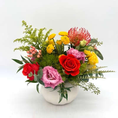 Colorful mixed flower arrangement in a white vase