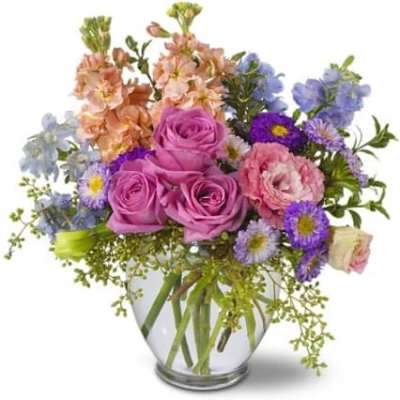 Mixed bouquet of pink roses and purple flowers in a glass vase
