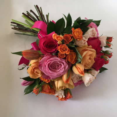 Colorful bouquet of roses and tulips with a pink ribbon