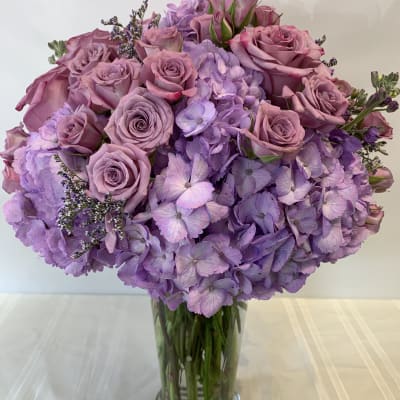 Lavender roses and hydrangeas in a clear glass vase