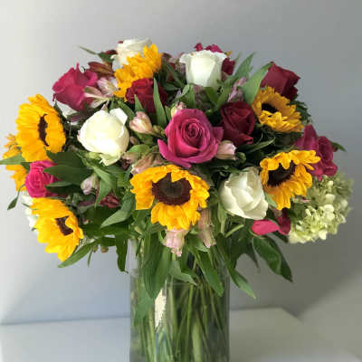 Bouquet of pink and white roses with sunflowers in a glass vase