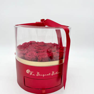 Red roses in a clear round gift box with a red ribbon