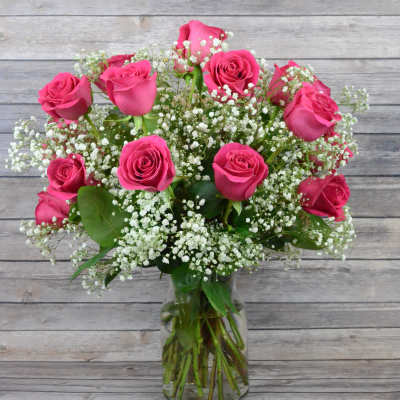 Pink roses arranged with white baby's breath in a clear glass vase