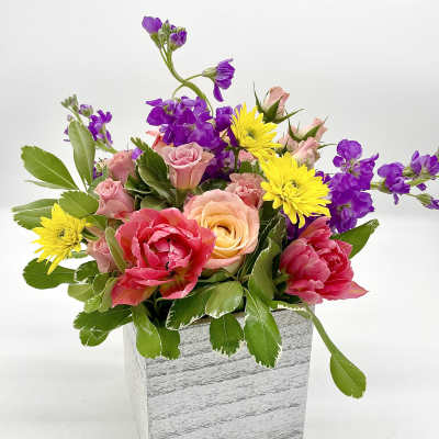 Mixed bouquet in a white wooden box with pink, yellow, and purple flowers