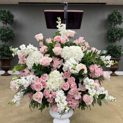 Large pink and white floral arrangement in a white pedestal vase