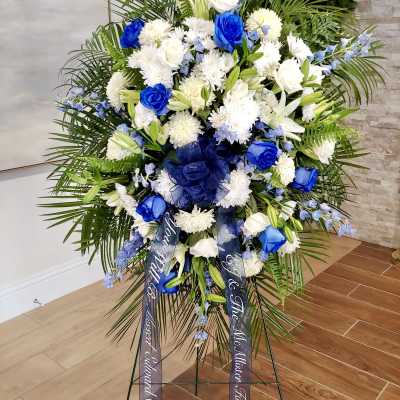 Large standing floral spray with blue and white flowers on an easel