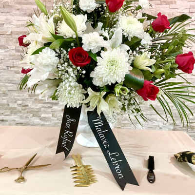 White and red floral arrangement in a vase with name ribbons