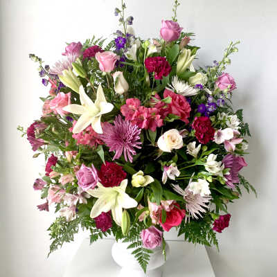 Large mixed bouquet of pink, white, and purple flowers in a white vase