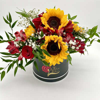 Red roses and sunflowers arranged in a round black box