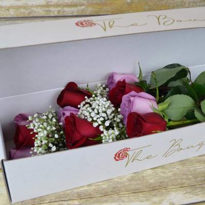 Boxed bouquet of red and lavender roses with baby's breath