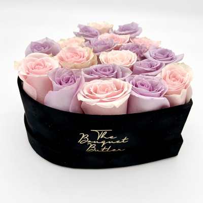 Pink and lavender roses arranged in a black hat box