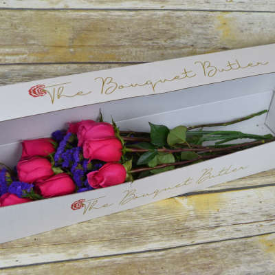 Boxed bouquet of pink roses with purple filler flowers