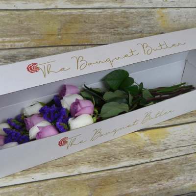 Boxed bouquet of lavender and white roses with purple filler