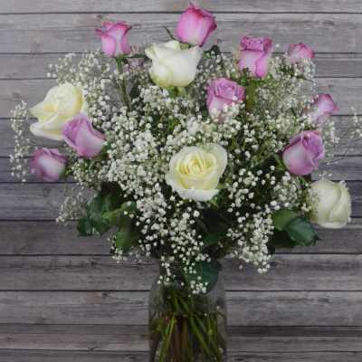 Pink and white roses in a glass vase with baby's breath