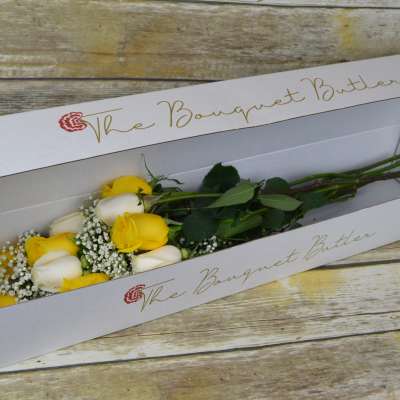 Yellow and white roses in a long white box