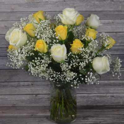 Yellow and white roses in a glass vase with baby's breath