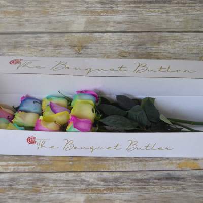 Box of multicolored roses with dark green leaves