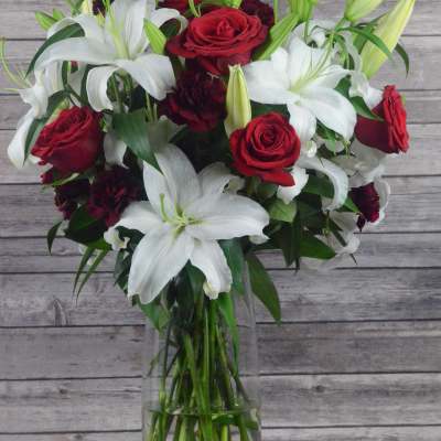 Bouquet of red roses and white lilies in a clear glass vase