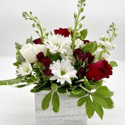 Red roses and white daisies arranged in a white wooden box