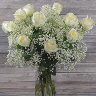 White roses and baby's breath in a clear glass vase