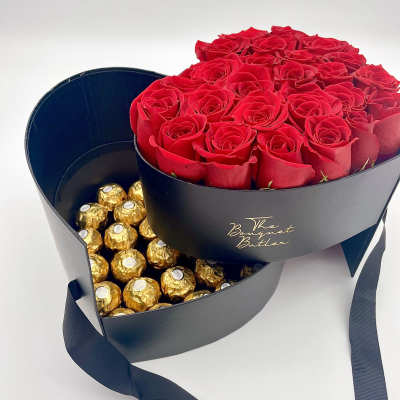 Red roses in a black heart-shaped box with gold-wrapped chocolates