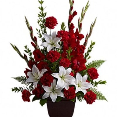 Red carnations and white lilies arranged in a dark vase