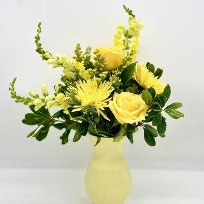 Yellow roses and spider mums in a pale yellow vase