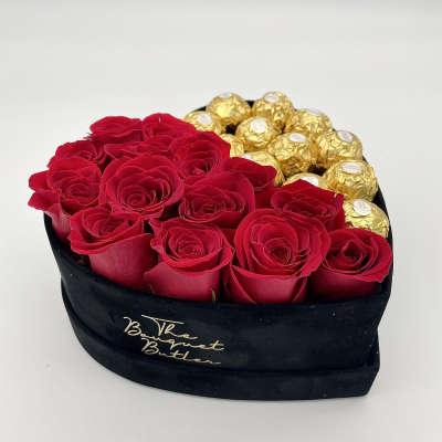 Red roses and gold-wrapped chocolates in a black heart-shaped box