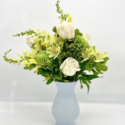 White and green floral arrangement in a pale blue vase