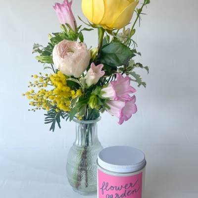 Mixed bouquet in a glass vase beside a pink candle tin