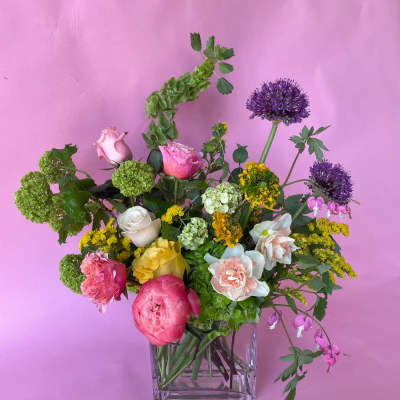 Mixed bouquet in a clear square vase with pink, yellow, white, and purple blooms