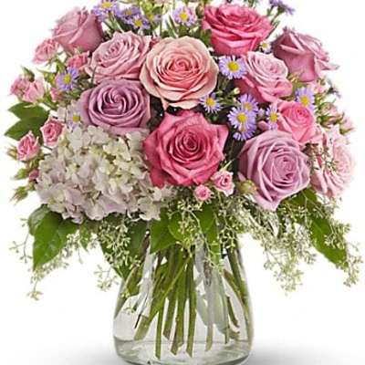 Pink and lavender roses with small purple flowers in a glass vase