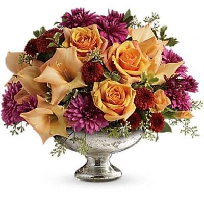 Mixed bouquet of orange roses, beige calla lilies, and purple mums in a silver vase